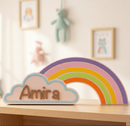 Rainbow and cloud decoration with 'Amira' on a shelf in a child's room.